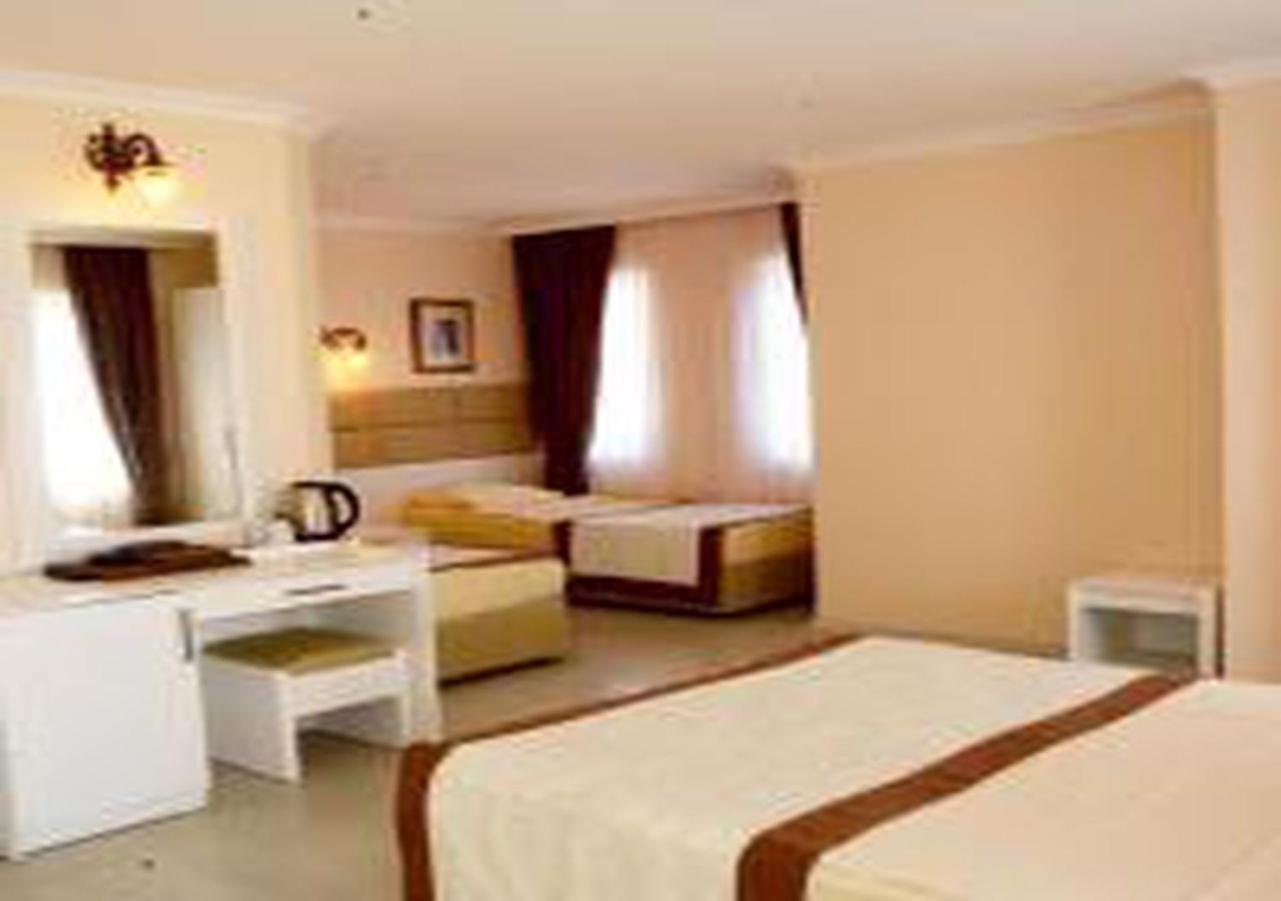 Miramor Hotel & Spa Antalya Extérieur photo The photo shows a hotel room with two beds and a cozy, inviting atmosphere. One bed is larger, possibly a queen or king size, and is draped with a light-colored bedspread that has a brown accent. The room has light-colored walls and natural light str